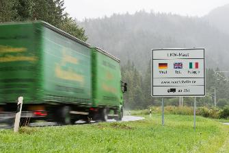 
Znak ustawiony przy drodze informuje o obowiązku uiszczania opłat drogowych od samochodów ciężarowych w Niemczech